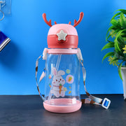 A pink and clear water bottle with a bunny design, deer antlers, and a colorful strap, against a background.