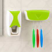 White and lime green automatic toothpaste dispenser and toothbrush holder mounted on a tiled wall with three toothbrushes.