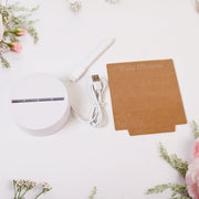 The disassembled lamp components: a white round base, a USB cable, a white marker, and a brown acrylic board, surrounded by