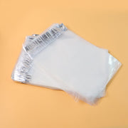 A stack of clear polybags with silver adhesive strips, angled on a light orange background.