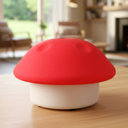 Red and white mushroom night light on a wooden table in a brightly lit living room.