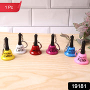 Six mini hand bell keychains in different colors with phrases, arranged on a wooden surface against a white tiled background.