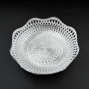 A silver plastic scalloped serving bowl with a textured bottom is centered on a black background.