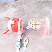 A pink and clear water bottle with a bunny design, lying on its side, showing the detachable strap.