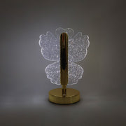A glowing crystal butterfly-shaped table lamp with a gold base and stem, centered on a plain gray background.