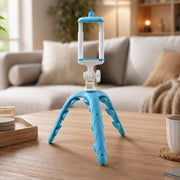A blue and white flexible tripod for phones standing on a wooden coffee table in a modern living room setting.