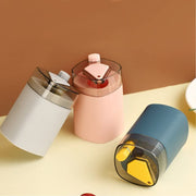 Three automatic toothpick dispensers, one grey, one pink, and one teal, are arranged on a light brown surface.