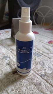 A white bottle with a blue label for shoe and sock deodorant stands on a patterned surface.