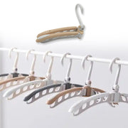 A row of white, beige, and gray folding hangers on a white clothing rack. An inset shows a folded hanger.