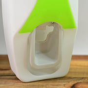 Close-up of the white and lime green automatic toothpaste dispenser showing the internal mechanism on a wooden surface.