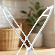 Close-up of the top portion of the white plastic bag holder, with a plant in the background.
