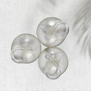 Three transparent suction cup hooks are arranged on a white textured surface with a subtle shadow.