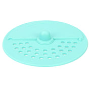 A light green silicone drain strainer with a central knob and two sections of holes is shown from above.