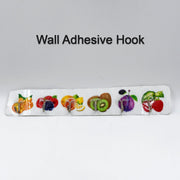 A white adhesive wall hook strip with fruit designs is centered on a plain white background with the text 