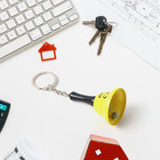 A yellow mini hand bell keychain with the phrase 