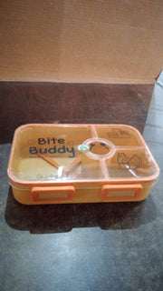 Closed yellow 4-compartment lunch box with clear lid and orange accents on a dark surface.