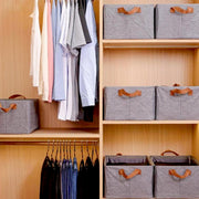 A wooden closet with hanging clothes and multiple grey fabric storage boxes on shelves.