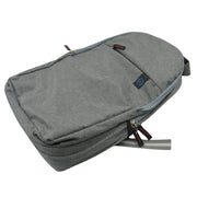 A grey backpack with a mesh side pocket and red-accented zippers lies on a white surface.