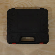 A closed black plastic carrying case with orange latches rests on a light wooden surface.