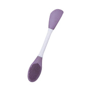 A single purple and white double-headed silicone mask brush on a white background.
