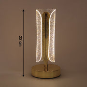 A lit gold and clear crystal table lamp with a curved design, showing a height measurement of 22 cm.