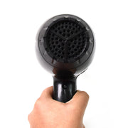 A hand holds a black hair dryer, showing a close-up of the circular air intake grill at the back.