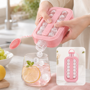 A person dispenses spherical ice cubes from a pink bottle into a glass of pink drink with lemon and mint. Inset shows the