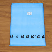 A light blue polybag with black arrow designs and a white label, on a wooden surface.