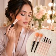 A woman applies blush with a large, soft, peach-colored makeup brush in a vanity setting.