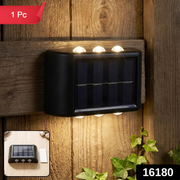 A black solar-powered LED wall light illuminates a wooden fence and green ivy at night, with a '1 Pc' label and '16180'