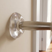 A clear silicone wall protector is adhered to a light beige wall, positioned behind a brushed metal door handle.