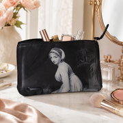 Black cosmetic bag with a classical portrait of a woman, surrounded by makeup and flowers.