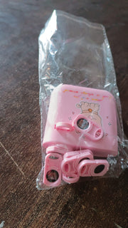 The pink puppy projector and its slide cartridges are sealed in clear plastic packaging on a wooden surface.