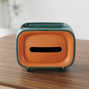 Green and orange rectangular tissue box with a wide opening on a wooden table.