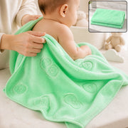 A baby is being dried with a light green microfiber towel featuring embossed heart and flower patterns.