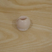 A single white toothbrush holder clip resting on a light brown wooden surface.