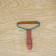 Pink and blue lint remover with textured handle for removing pet hair and lint from fabric.