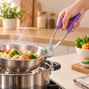 A hand holding a stainless steel pot lifter with purple handles, lifting a bowl of vegetables from a steamer.
