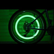 A bicycle wheel with a bright green glowing ring, viewed from the side in a dark setting.