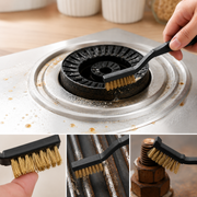 A hand uses a black-handled brass wire brush to clean a dirty gas stove burner.