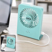A mint green portable desk fan connected to a laptop via a white USB cable, with a close-up inset.
