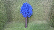 Blue microfiber duster with a black handle standing upright on a green artificial grass background.