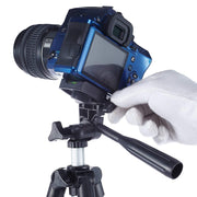A gloved hand adjusts a blue camera mounted on a black and silver tripod against a white background.