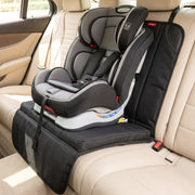 A gray and black child's car seat is secured on a black protector covering a beige vehicle seat.