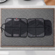 The black car seat protector is spread out on a textured gray mat with a wooden border.