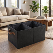A black foldable fabric storage basket with two compartments sits on a rug in a living room setting.