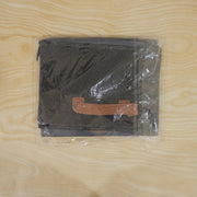 A dark gray foldable fabric storage basket with a brown handle, folded and sealed in clear plastic packaging.