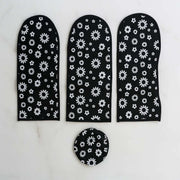 Three long black and white floral dust covers and one round cover arranged on a white marble surface.