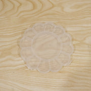Empty clear flower-shaped plastic organizer box with 13 compartments on a light wood grain surface.