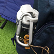 A silver D-ring carabiner with a screw lock is attached to a blue backpack, holding a water bottle.